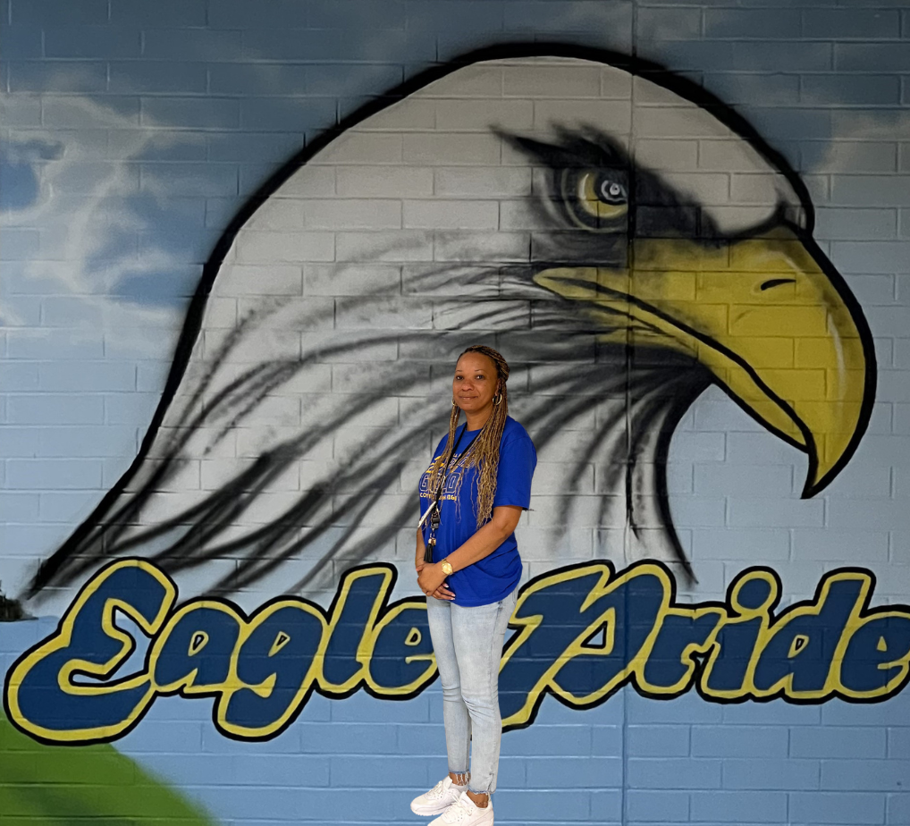 Mrs. Alisha Wells standing in front of the eagle pride mural at SBMS.