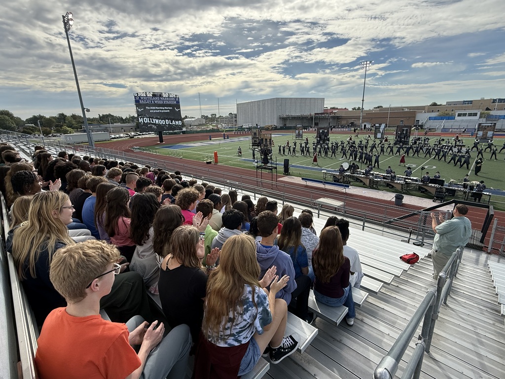 students in the stands watching the marching band