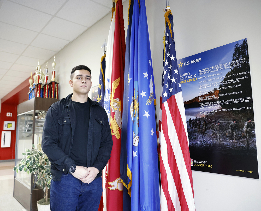 JROTC student standing next to flags