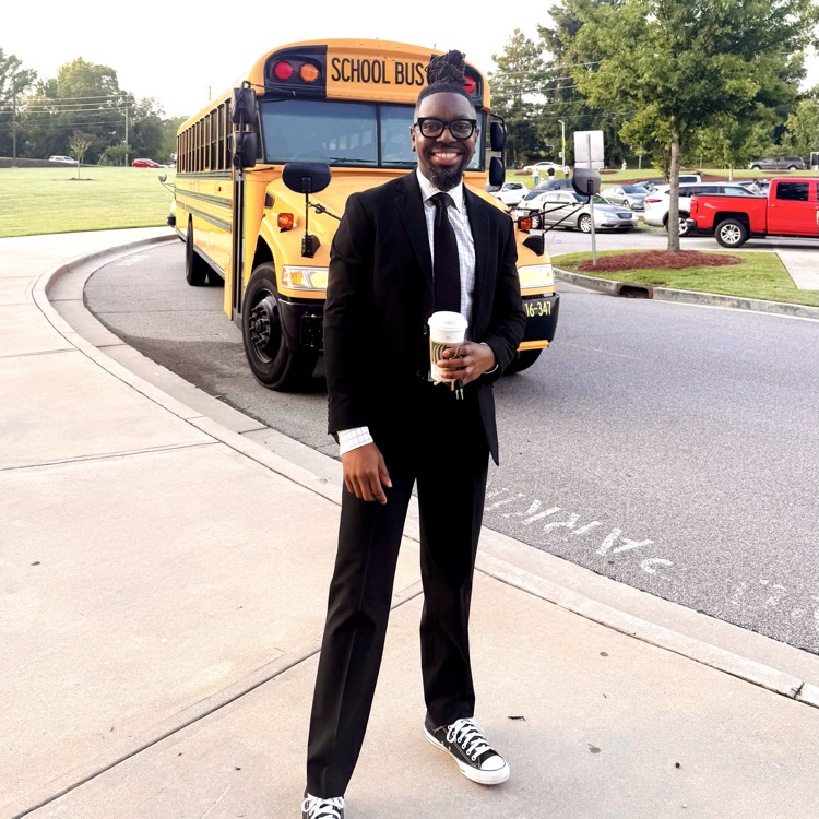 principal stands in front of a school bus 