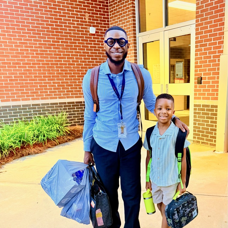 a father and son bring school supplies into the building