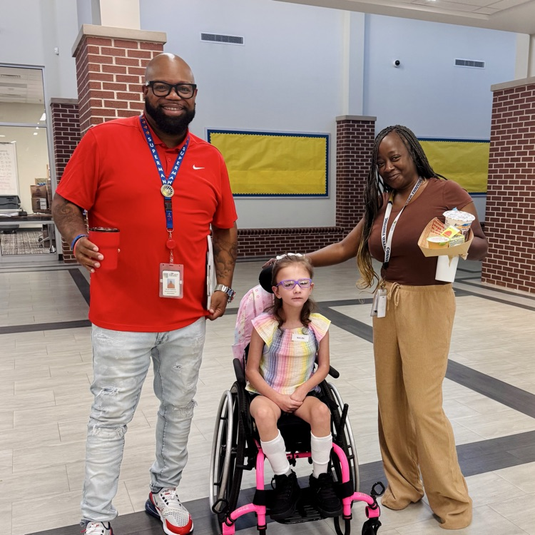 two staff members pose with a girl in a wheelchair