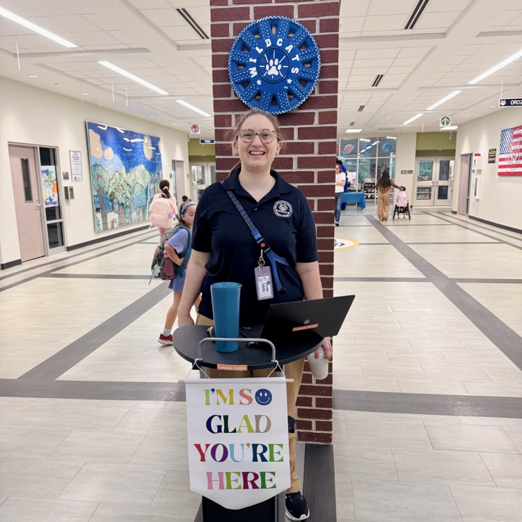 a school counselor stands welcoming students