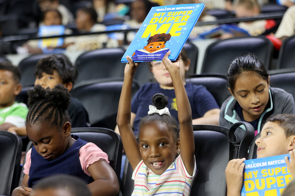 Girl holding up Malcolm Mitchell book and smiling