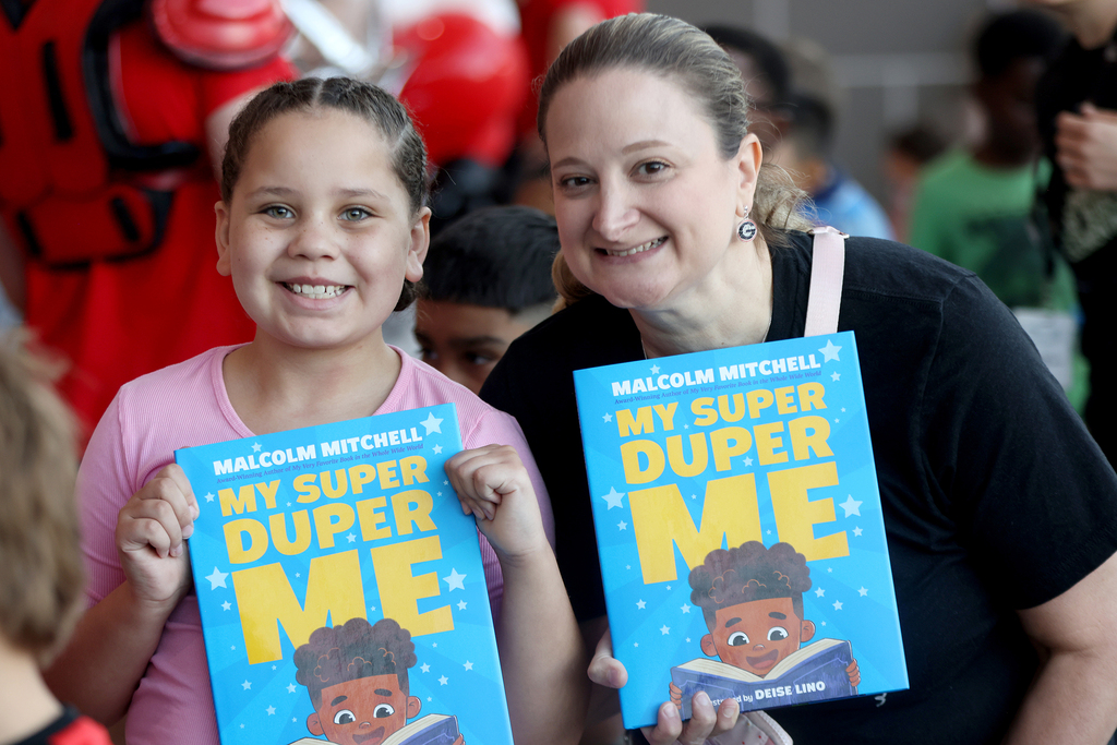 Teacher and student holding up books and smiling