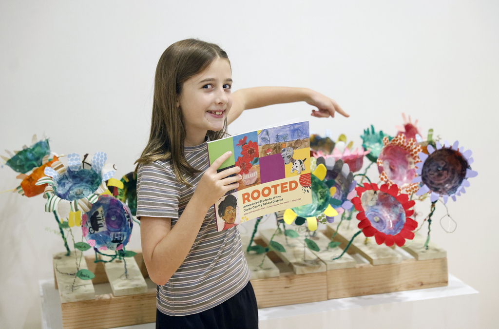 Student holding up art book and pointing to art