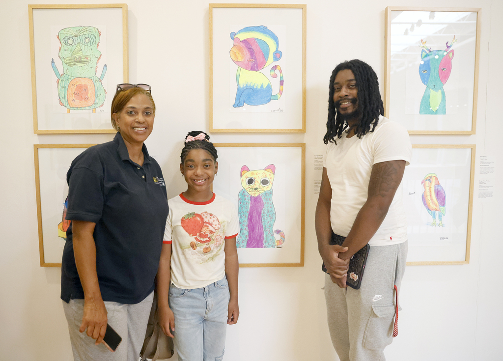Student posing in front of art with family