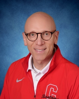 man with glasses in red jacket with a C on it