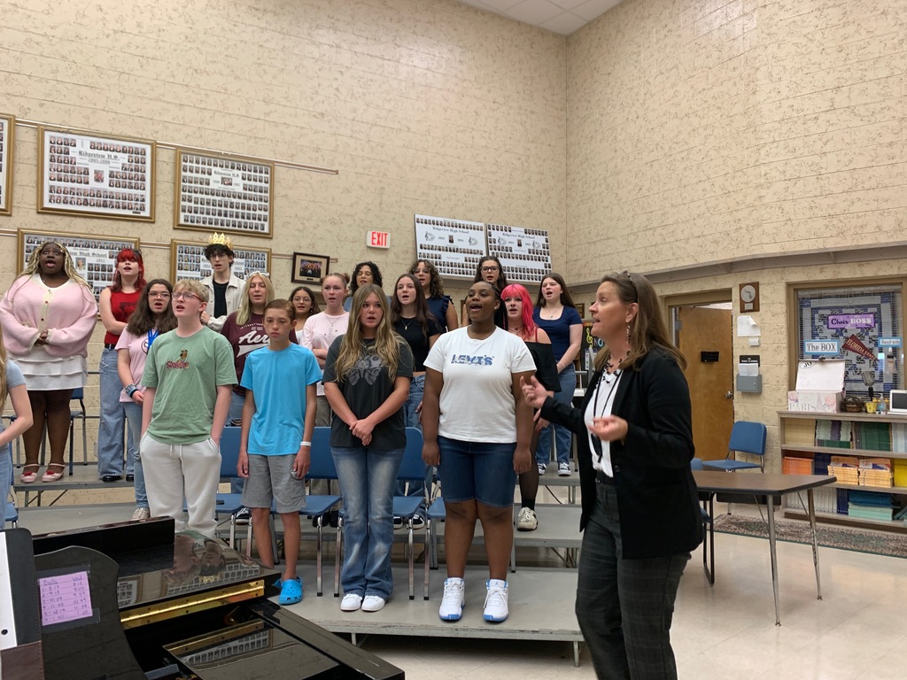 Students in Beginning Chorus stand and sing together in the classroom on the first day of school, smiling and engaged in the activity.