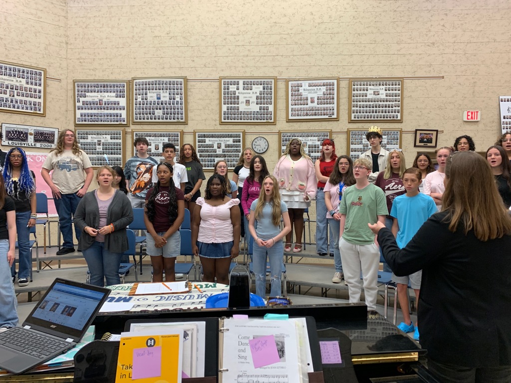 Students in Beginning Chorus stand and sing together in the classroom on the first day of school, smiling and engaged in the activity.
