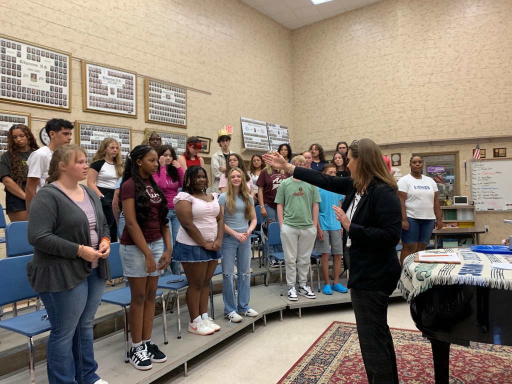 Students in Beginning Chorus stand and sing together in the classroom on the first day of school, smiling and engaged in the activity.