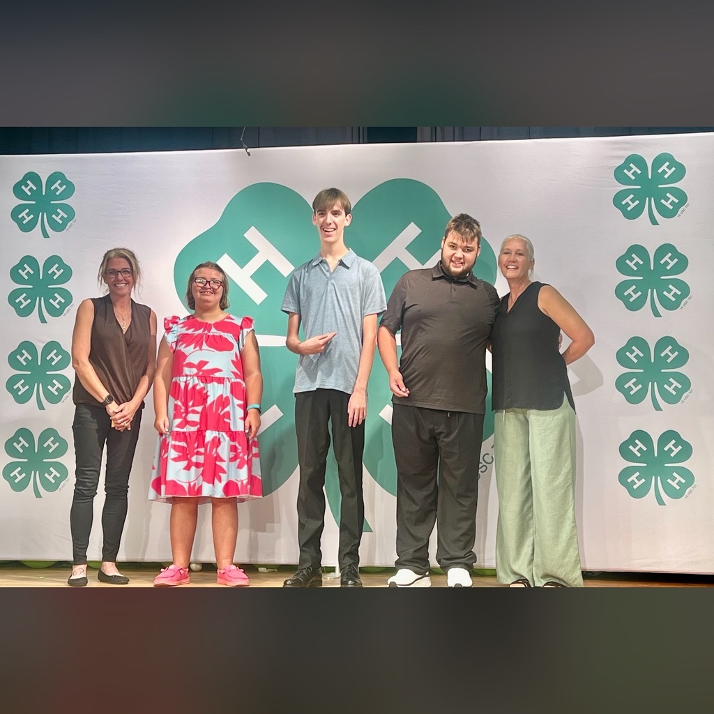 Three Ridgeview High School Bright Learners 4H Club members stand proudly with their leaders, Ms. Cannarella and Ms. Wilson, in front of a large green 4H clover backdrop at the Clay County 4H Award Banquet.