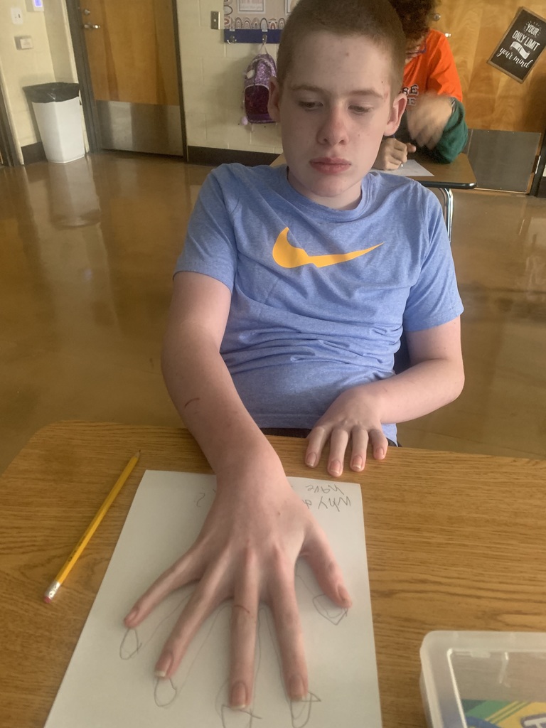 Student closely examining their hand while beginning Step 1 of the scientific method.
