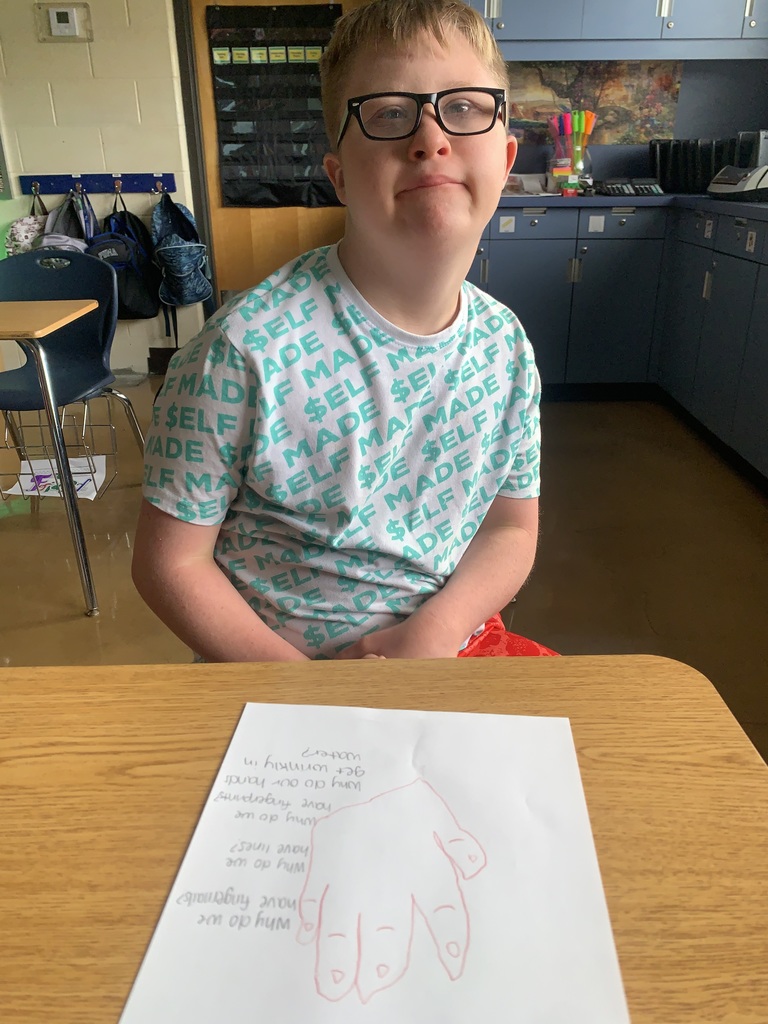 Student closely examining their hand while beginning Step 1 of the scientific method.