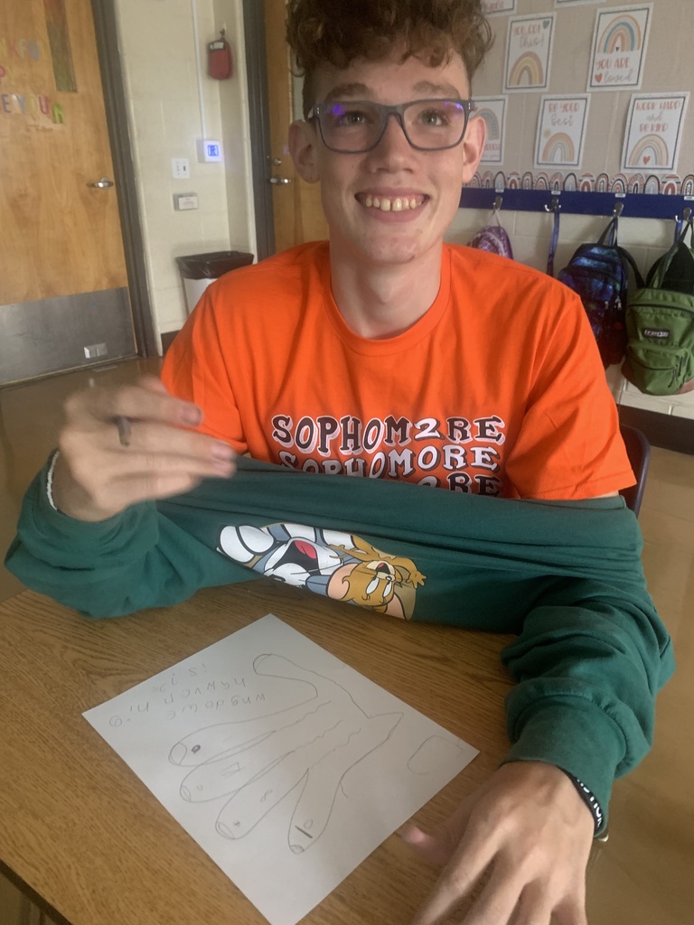 Student closely examining their hand while beginning Step 1 of the scientific method.