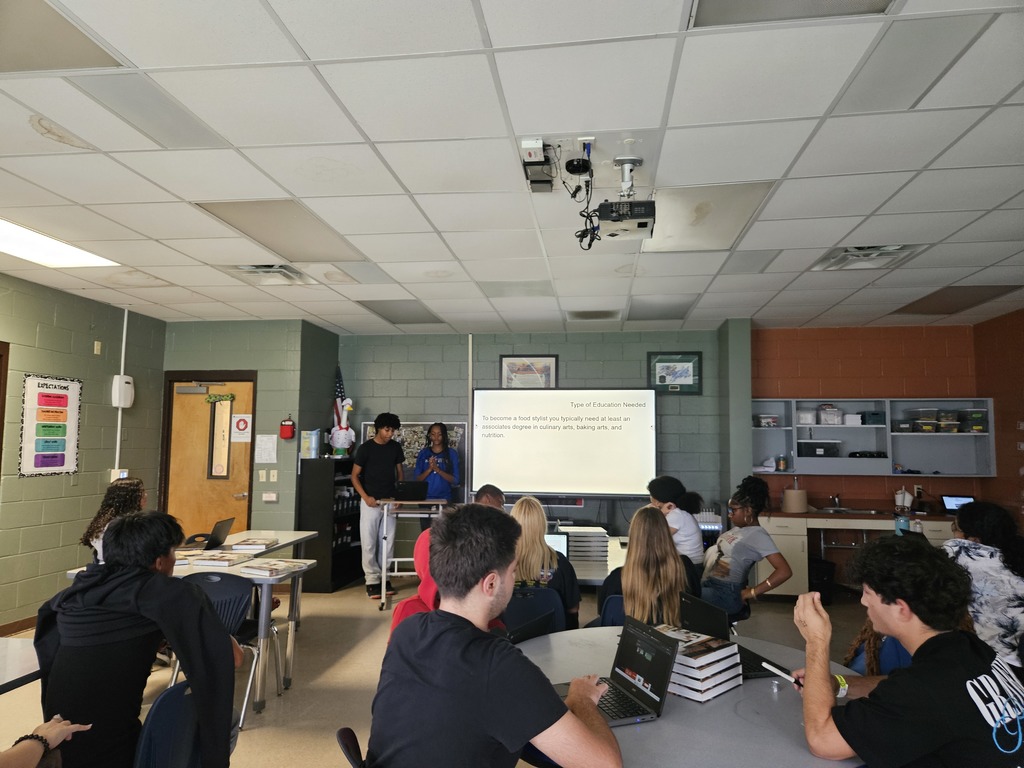 Student presenting research on a culinary career pathway while classmates listen.