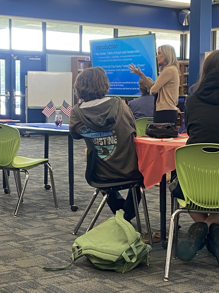 Students seated and listening attentively to a Constitution Week presentation in the media center.