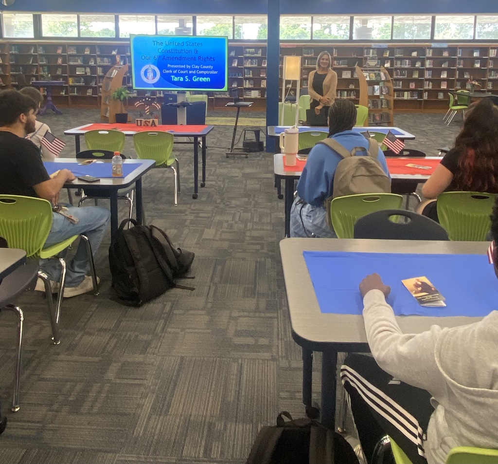 Students seated and listening attentively to a Constitution Week presentation in the media center.