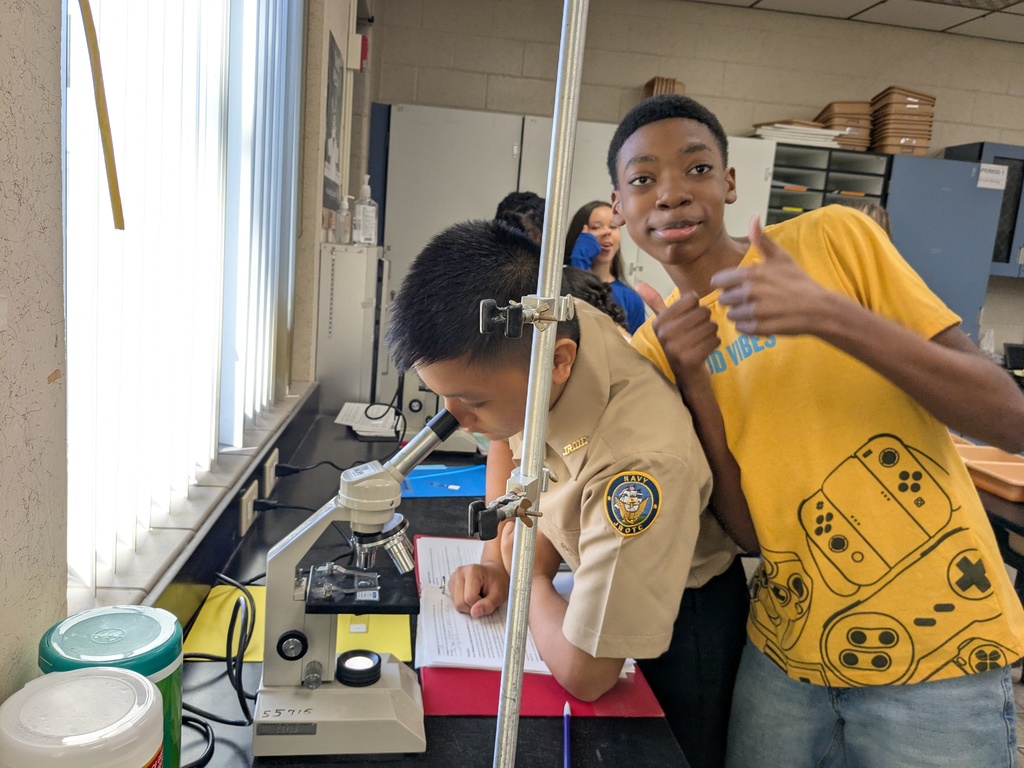 Students using microscopes in a classroom lab to observe and measure plant and bacteria cells.