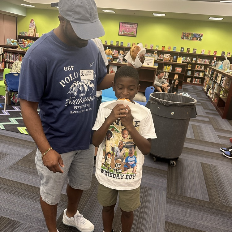 Dad watching son eat doughnut