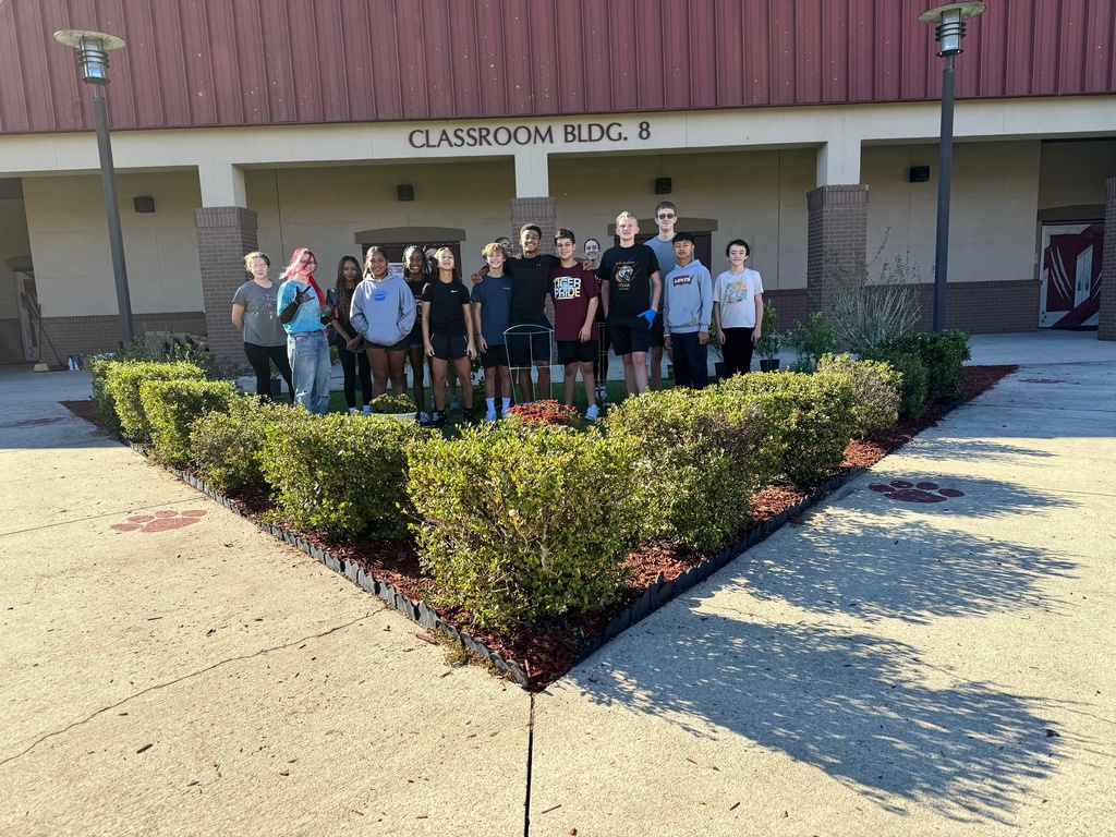 Students are posed together in the middle of the garden plot toward the end of their work.