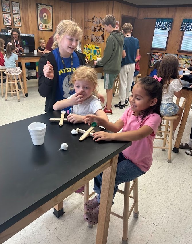 6th grade and Kindergarten have both been working on Force and Motion this quarter. Today they paired up in our Science Lab to use catapults, built by 6th graders, to launch cotton balls at targets with our K friends….It was awesome!