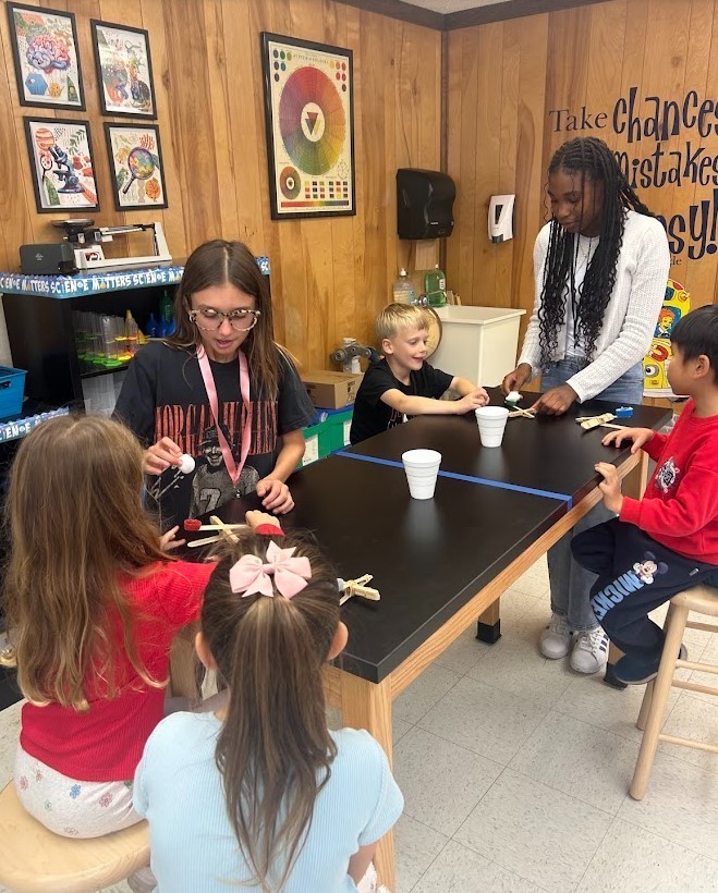 6th grade and Kindergarten have both been working on Force and Motion this quarter. Today they paired up in our Science Lab to use catapults, built by 6th graders, to launch cotton balls at targets with our K friends….It was awesome!