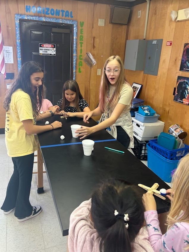 6th grade and Kindergarten have both been working on Force and Motion this quarter. Today they paired up in our Science Lab to use catapults, built by 6th graders, to launch cotton balls at targets with our K friends….It was awesome!