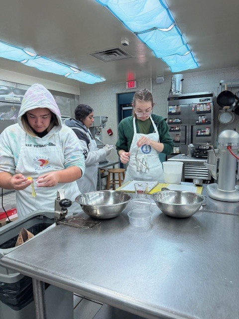 Culinary students in 3 and 4 took on a sweet, multi-day project, crafting homemade ice cream sandwiches from start to finish. On day one, students prepared their ice cream base and mise-en-place for their cookies. Day two focused on churning the ice cream, freezing it on sheet pans, and baking fresh cookies. On the final day, students used cookie cutters to shape the ice cream, assembled their sandwiches, and finished them off with a chocolate dip, bringing creativity, precision, and delicious results together.