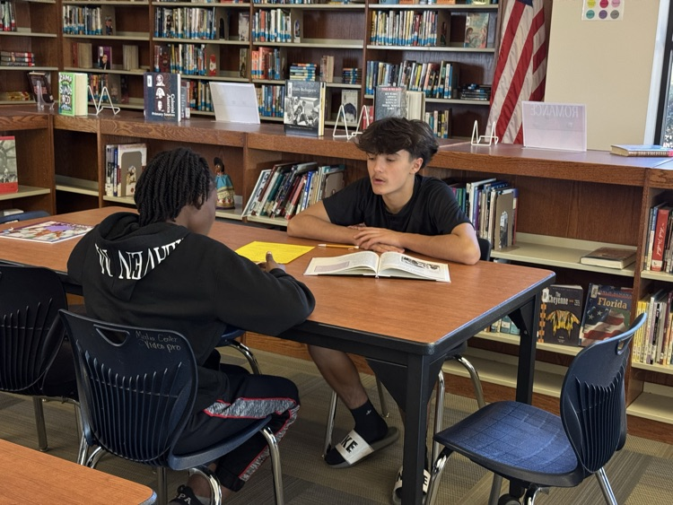 student reading a text to a peer.