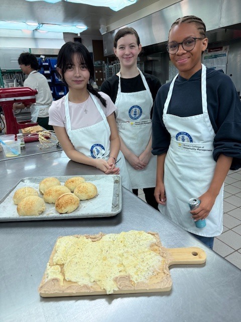 Our Culinary 3 and 4 students recently took on the challenge of creating their own bread-and-butter boards from scratch! Students began by researching a bread recipe that could be completed within two days. On day one, they prepared the dough and placed it in the refrigerator to slow the rise. On day two, they shaped and baked their loaves, then created a flavored butter of their choice. From sweet to savory, the variety of butters paired perfectly with the freshly baked bread. To finish, students arranged their creations on wooden cutting boards for a beautiful presentation. It was a hands-on lesson in patience, technique, and creativity, and the results were delicious! 