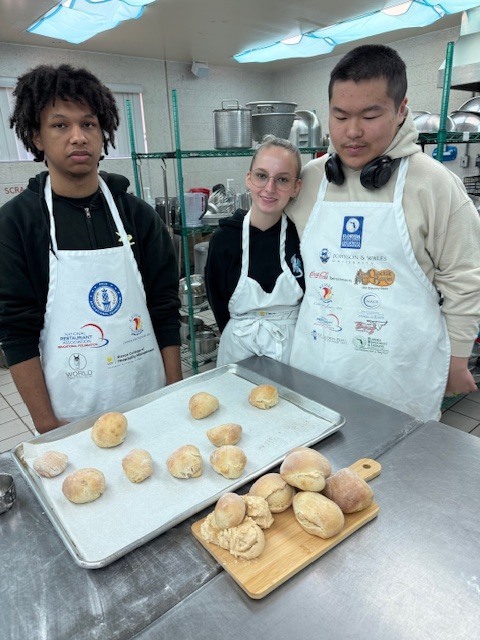 Our Culinary 3 and 4 students recently took on the challenge of creating their own bread-and-butter boards from scratch! Students began by researching a bread recipe that could be completed within two days. On day one, they prepared the dough and placed it in the refrigerator to slow the rise. On day two, they shaped and baked their loaves, then created a flavored butter of their choice. From sweet to savory, the variety of butters paired perfectly with the freshly baked bread. To finish, students arranged their creations on wooden cutting boards for a beautiful presentation. It was a hands-on lesson in patience, technique, and creativity, and the results were delicious! 