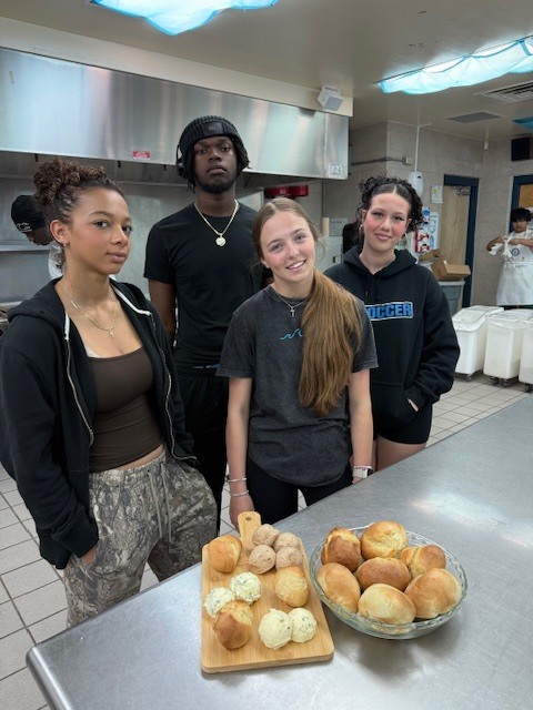 Our Culinary 3 and 4 students recently took on the challenge of creating their own bread-and-butter boards from scratch! Students began by researching a bread recipe that could be completed within two days. On day one, they prepared the dough and placed it in the refrigerator to slow the rise. On day two, they shaped and baked their loaves, then created a flavored butter of their choice. From sweet to savory, the variety of butters paired perfectly with the freshly baked bread. To finish, students arranged their creations on wooden cutting boards for a beautiful presentation. It was a hands-on lesson in patience, technique, and creativity, and the results were delicious! 