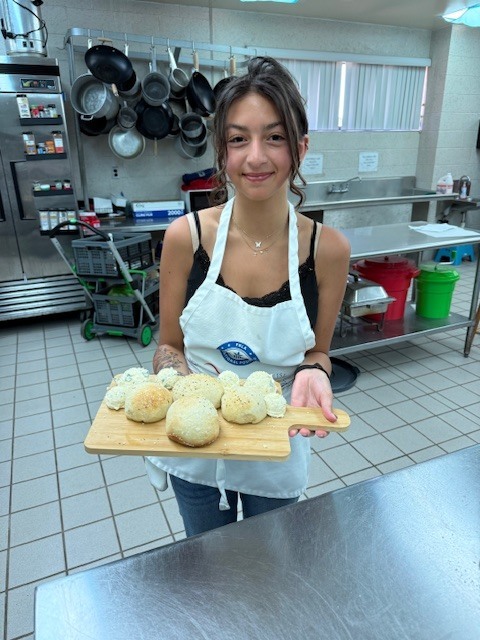 Our Culinary 3 and 4 students recently took on the challenge of creating their own bread-and-butter boards from scratch! Students began by researching a bread recipe that could be completed within two days. On day one, they prepared the dough and placed it in the refrigerator to slow the rise. On day two, they shaped and baked their loaves, then created a flavored butter of their choice. From sweet to savory, the variety of butters paired perfectly with the freshly baked bread. To finish, students arranged their creations on wooden cutting boards for a beautiful presentation. It was a hands-on lesson in patience, technique, and creativity, and the results were delicious! 