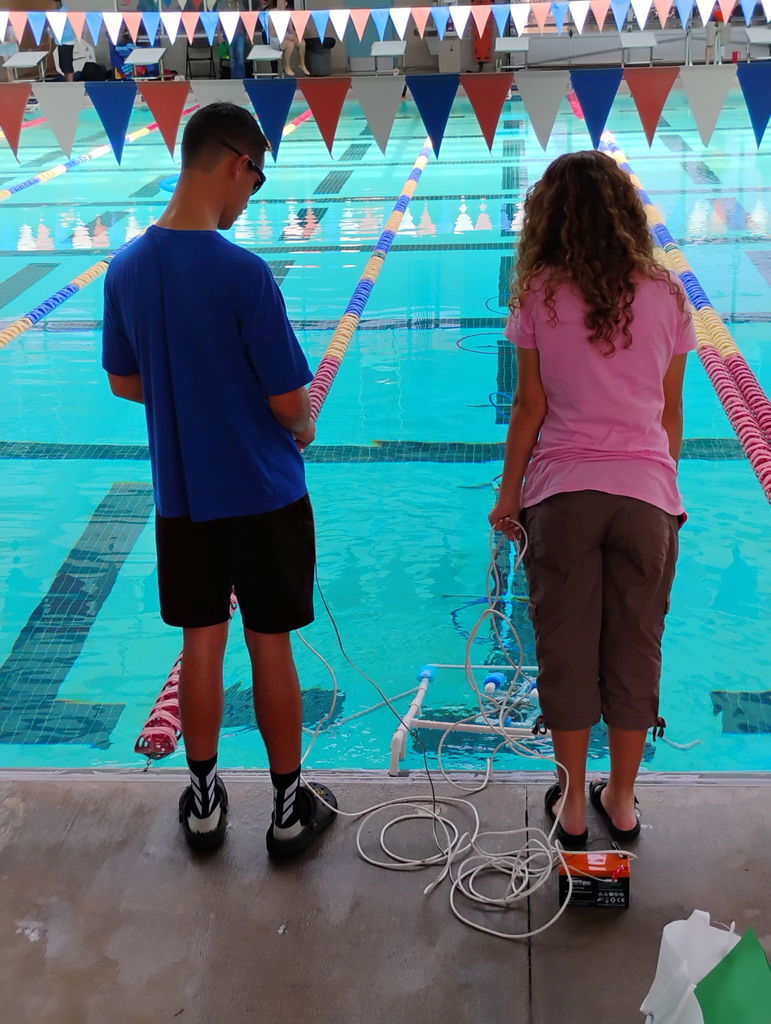 Students in front of a pool operating an ROV during a SeaPerch Competition.