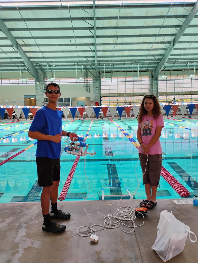 Students in front of a pool operating an ROV during a SeaPerch Competition.