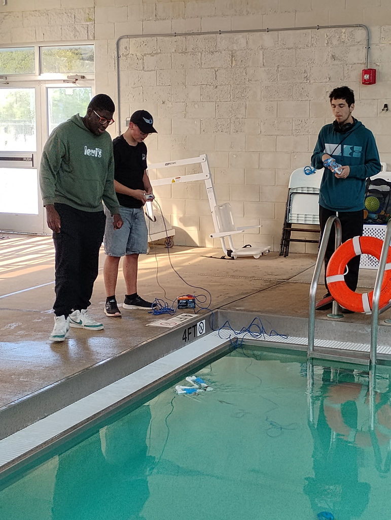Students in front of a pool operating an ROV during a SeaPerch Competition.