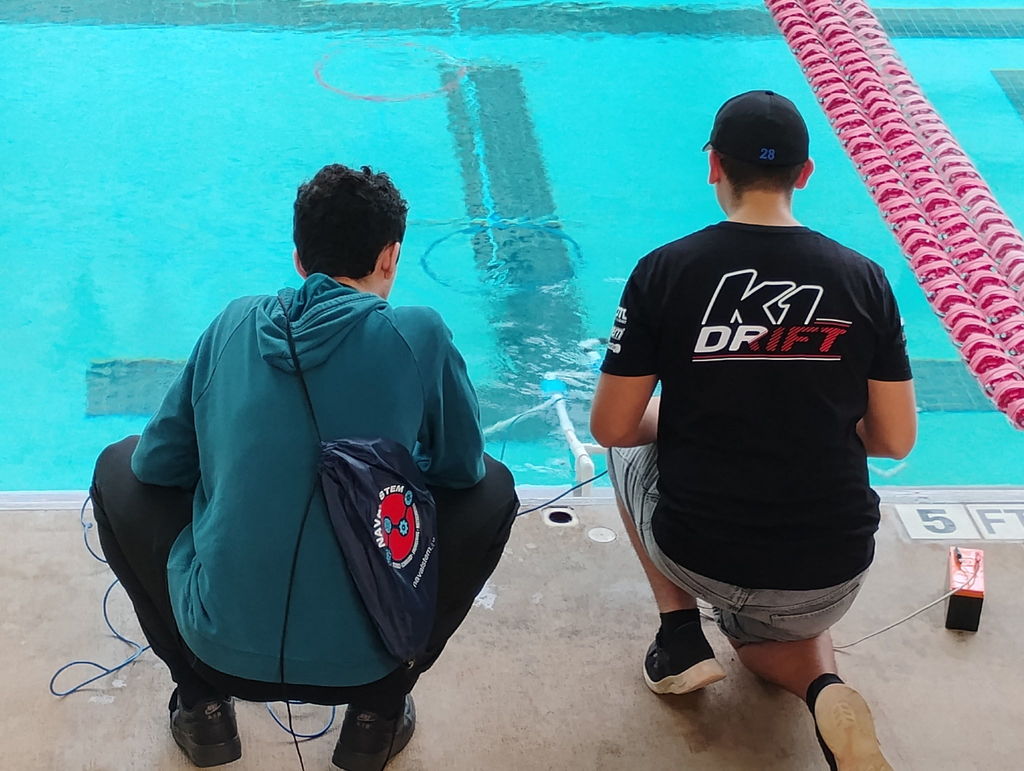 Students in front of a pool operating an ROV during a SeaPerch Competition.