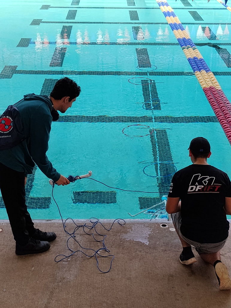 Students in front of a pool operating an ROV during a SeaPerch Competition.