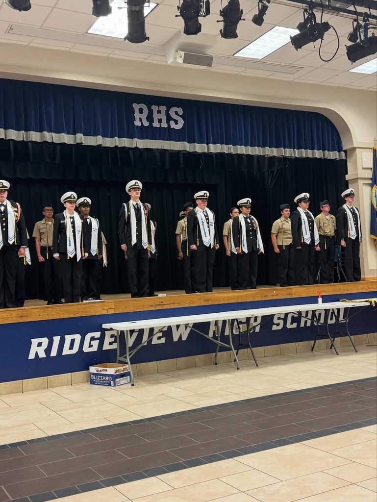 A group of uniformed individuals stands on a stage with a blue curtain and "RHS" behind them.