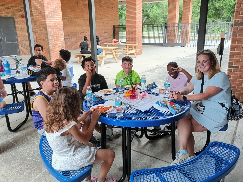 five students and a teacher sitting at a picnic table