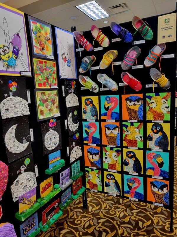 A wall displays artwork, including penguins, owls, and shoes. The wall is black with a yellow border.
