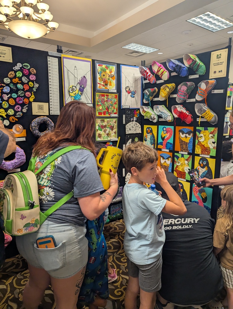 Two adults and two children are looking at an art display. The adults are wearing backpacks.