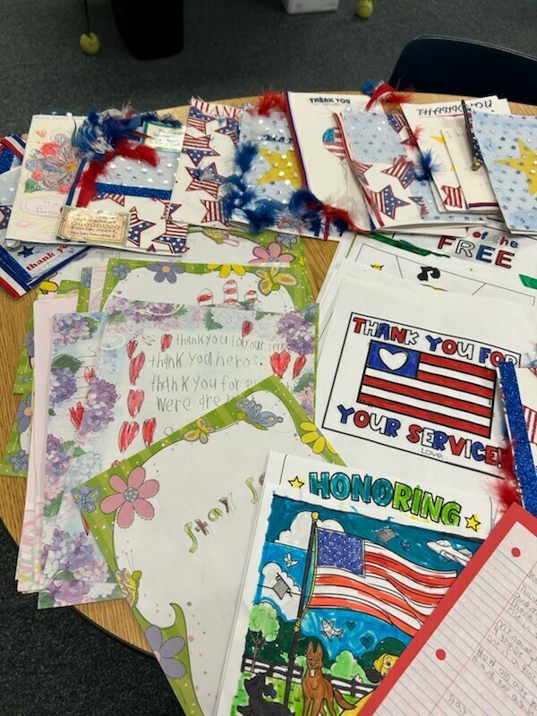 A collection of colorful, handmade cards and papers with patriotic designs and messages displayed on a table.