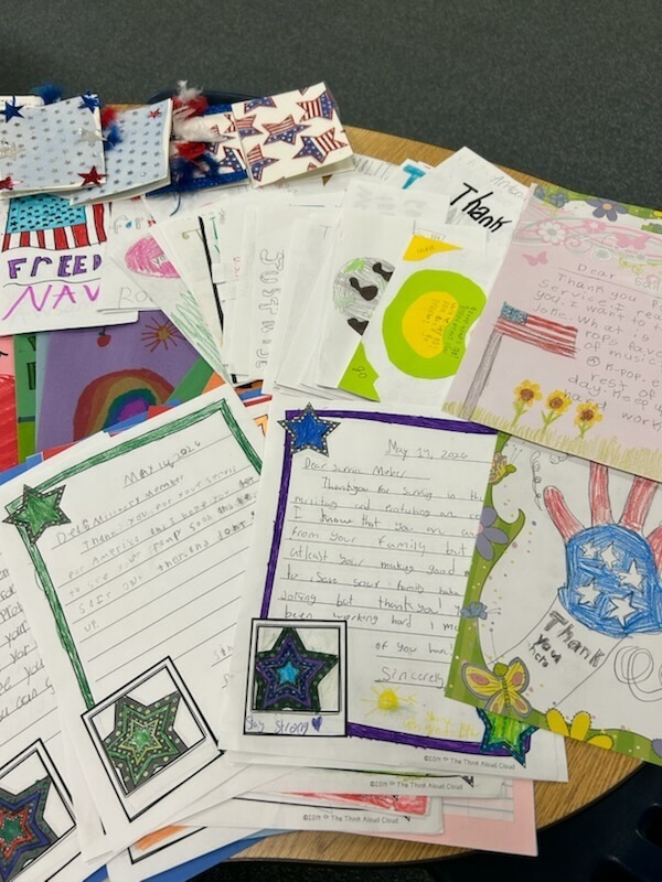 A table holds a variety of colorful, hand-drawn cards and papers, including stars, hearts, and patriotic designs.