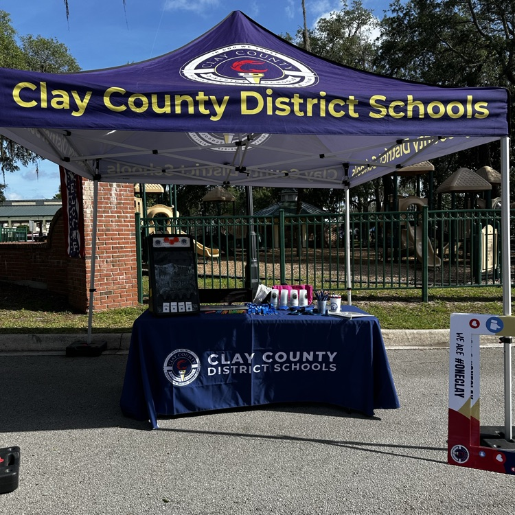 a Clay county district schools tent with a table and giveaways like pencils. 