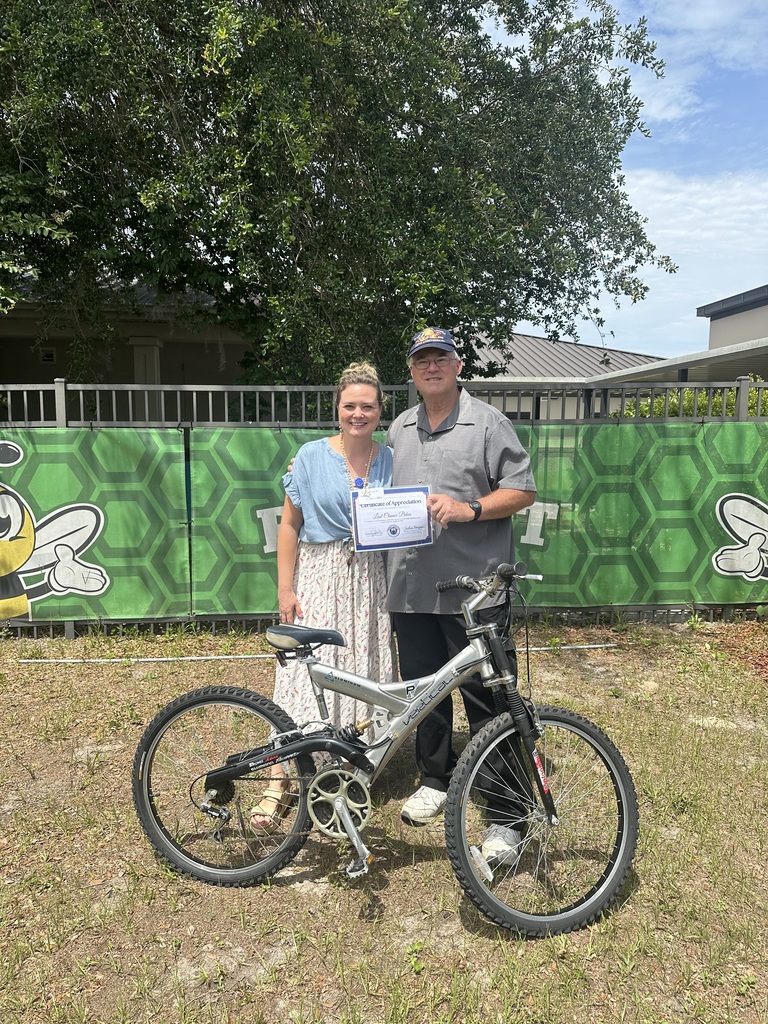 Two people standing next to a bicycle, holding a certificate.