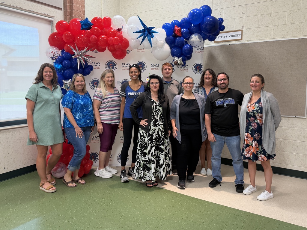 A group of people stand in front of a backdrop with balloons.