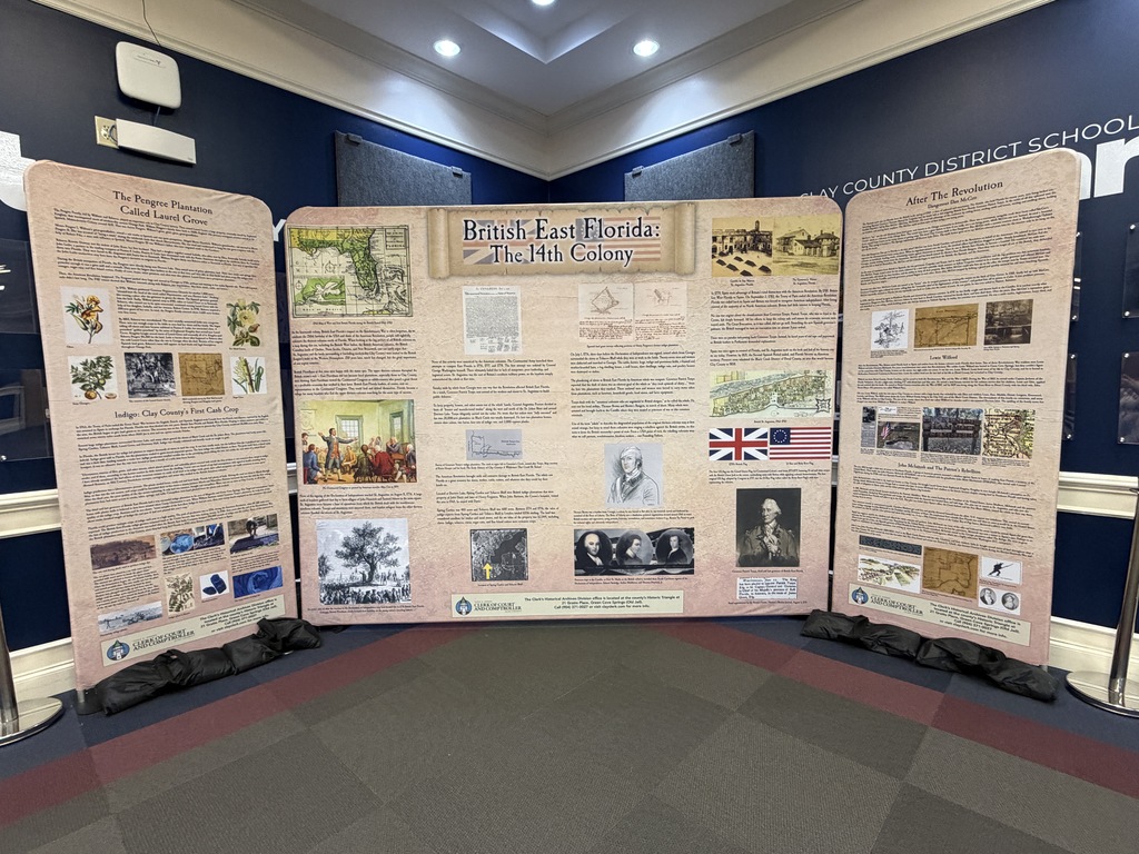 Large trifold display panels, featuring historical images and text, positioned on a tiled floor in a room with blue walls.