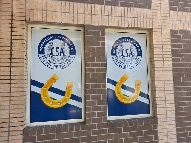 Two windows on a brick wall, each with a horseshoe logo and text. The horseshoes are yellow with blue backgrounds.